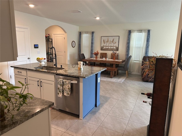 kitchen with white cabinetry, dishwasher, sink, dark stone counters, and a center island with sink