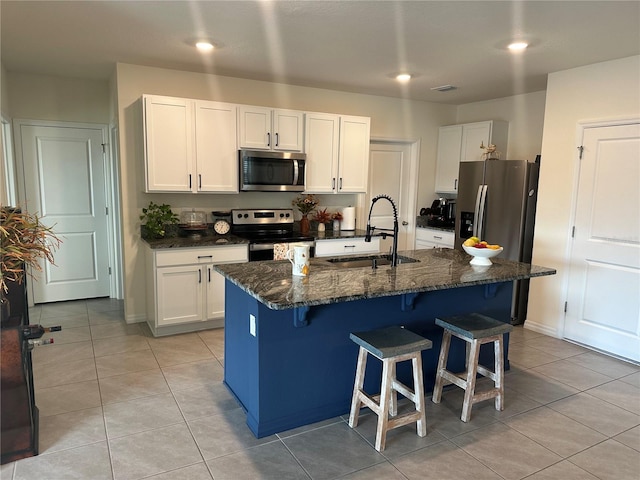 kitchen featuring appliances with stainless steel finishes, a kitchen breakfast bar, a kitchen island with sink, sink, and white cabinetry