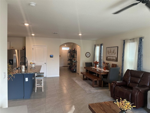 tiled living room featuring ceiling fan, a healthy amount of sunlight, and sink