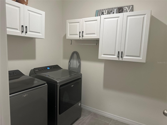 clothes washing area with separate washer and dryer, cabinets, and dark tile patterned flooring