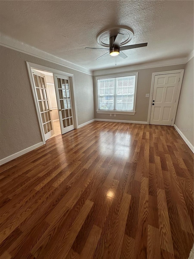 spare room with a textured ceiling, ceiling fan, dark hardwood / wood-style floors, and ornamental molding