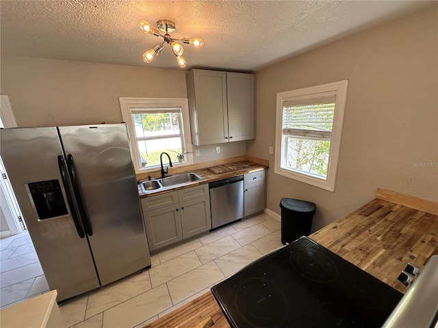 kitchen featuring gray cabinetry, sink, a chandelier, a textured ceiling, and appliances with stainless steel finishes