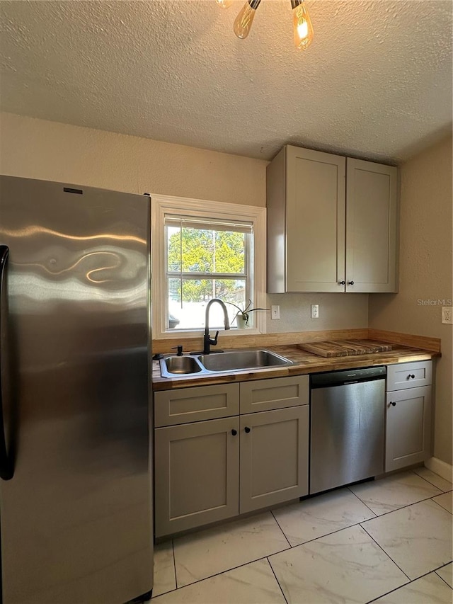 kitchen featuring gray cabinetry, sink, appliances with stainless steel finishes, and a textured ceiling