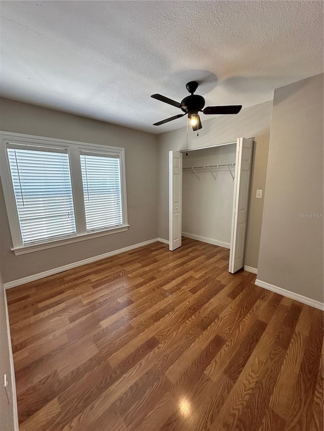 unfurnished bedroom with hardwood / wood-style flooring, ceiling fan, a textured ceiling, and a closet