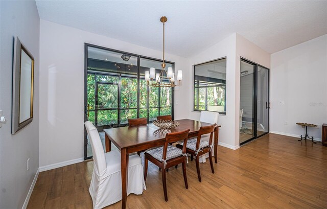 dining area with an inviting chandelier, baseboards, and wood finished floors