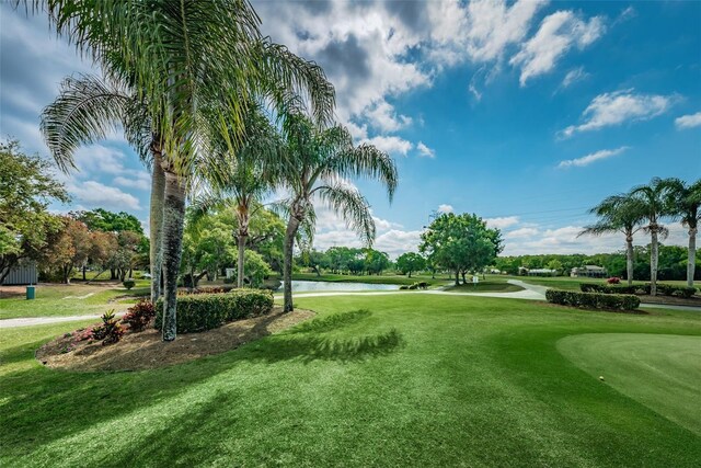 view of home's community with view of golf course, a water view, and a yard