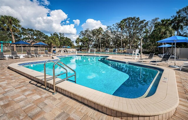 community pool with a patio area and fence