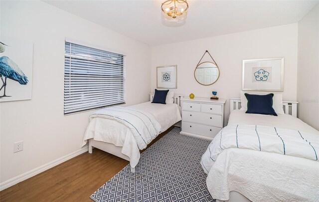 bedroom with a chandelier, baseboards, and wood finished floors