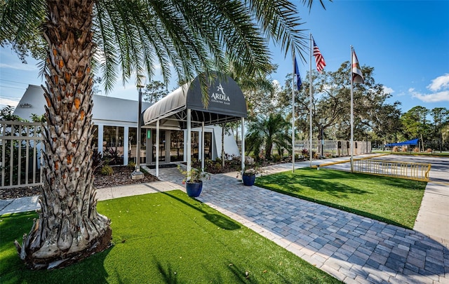 view of property's community with a lawn and fence