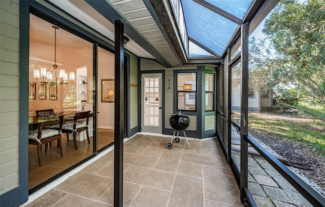 sunroom / solarium with lofted ceiling with skylight, a wealth of natural light, and a notable chandelier