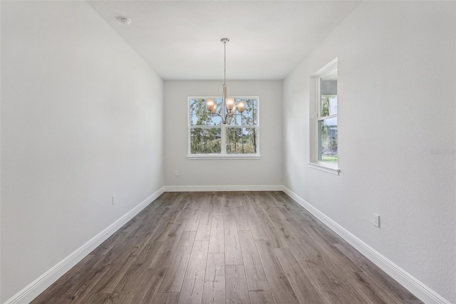 unfurnished dining area with hardwood / wood-style floors and an inviting chandelier