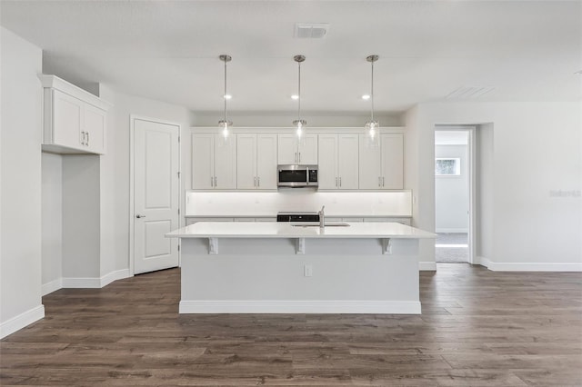 kitchen featuring decorative light fixtures, white cabinetry, a kitchen island with sink, and dark hardwood / wood-style floors