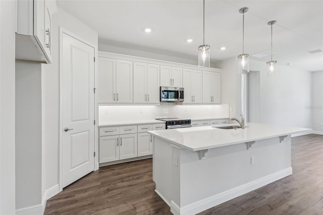 kitchen featuring white cabinetry, sink, stainless steel appliances, dark hardwood / wood-style flooring, and a center island with sink