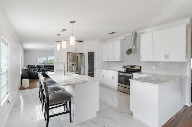 kitchen with hanging light fixtures, stainless steel appliances, a kitchen breakfast bar, backsplash, and white cabinets