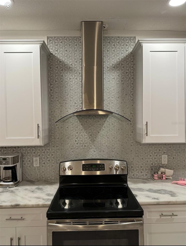 kitchen featuring decorative backsplash, white cabinetry, stainless steel electric stove, and wall chimney range hood