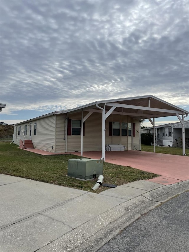 manufactured / mobile home with a front lawn and a carport