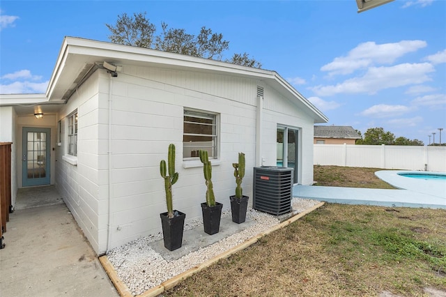 view of property exterior with a fenced in pool and central AC