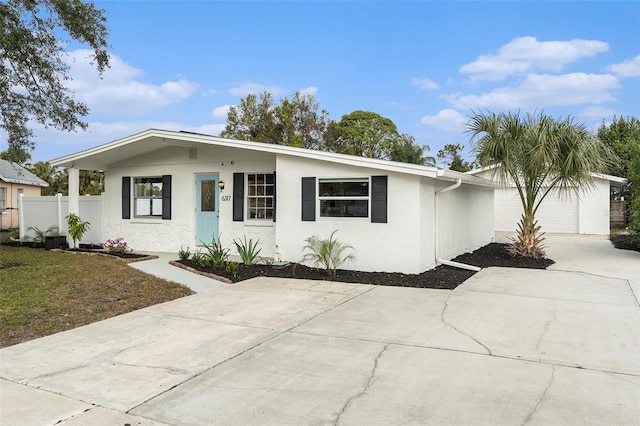 view of front facade with driveway, an attached garage, fence, and stucco siding