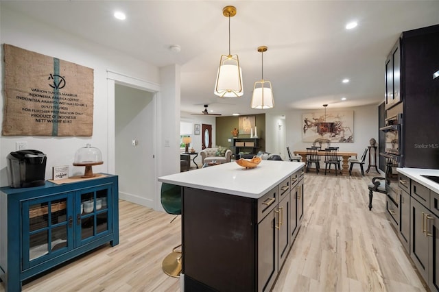 kitchen featuring pendant lighting, a center island, ceiling fan, light wood-type flooring, and a kitchen bar