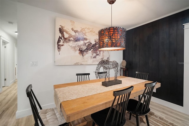 dining room with light wood-type flooring and wooden walls