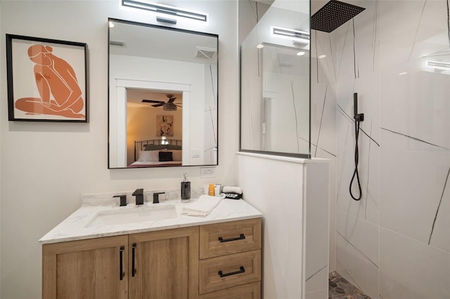 bathroom with a tile shower, vanity, and ceiling fan