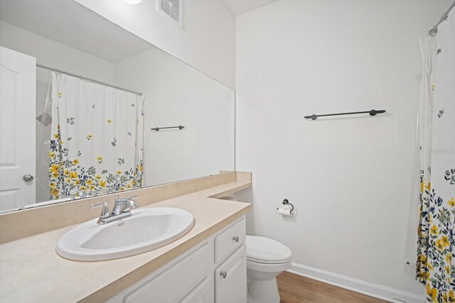 bathroom with hardwood / wood-style floors, vanity, and toilet