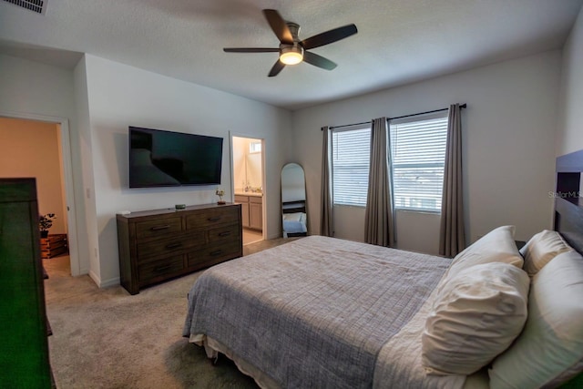 carpeted bedroom with ensuite bathroom, ceiling fan, and a textured ceiling