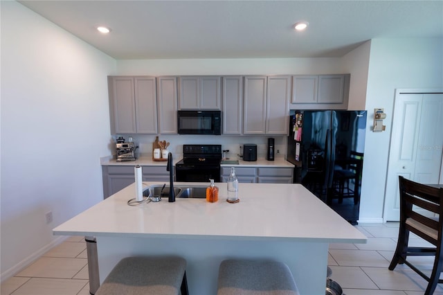 11834 Brighton Knoll Loop, Riverview, FL 33579 - kitchen featuring black appliances, gray cabinets, light countertops, light tile patterned floors, and a kitchen island with sink
