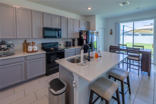 11834 Brighton Knoll Loop, Riverview, FL 33579 - kitchen with black appliances, gray cabinets, a kitchen bar, a center island with sink, and light countertops
