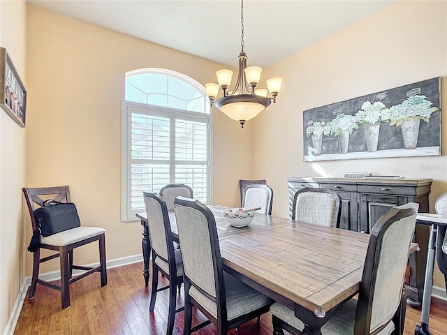 dining area with hardwood / wood-style floors and an inviting chandelier