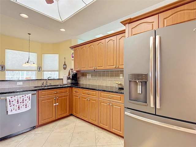 kitchen featuring sink, stainless steel appliances, tasteful backsplash, dark stone countertops, and decorative light fixtures