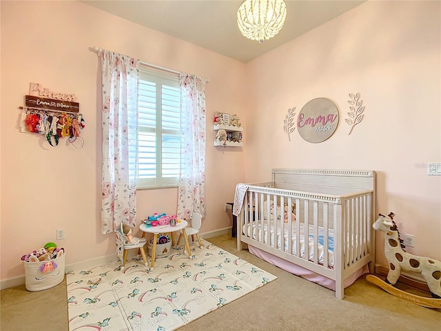 carpeted bedroom with a crib and an inviting chandelier