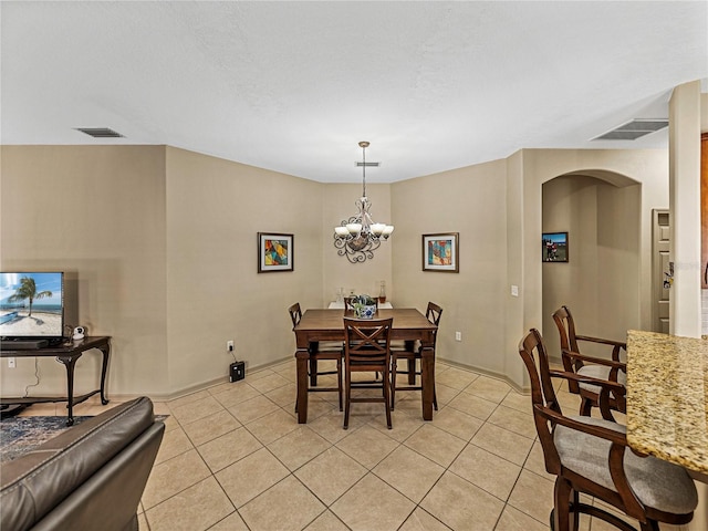 dining room featuring a textured ceiling, a notable chandelier, and light tile patterned flooring