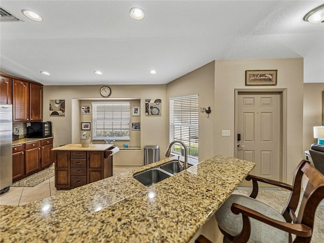 kitchen featuring stainless steel fridge, sink, a kitchen island, and a healthy amount of sunlight