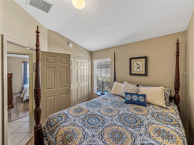 bedroom featuring hardwood / wood-style flooring, vaulted ceiling, a textured ceiling, and a closet