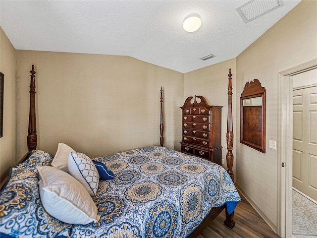 bedroom featuring lofted ceiling, wood-type flooring, and a textured ceiling