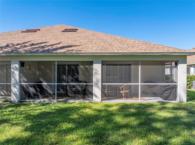 rear view of property featuring a sunroom and a lawn