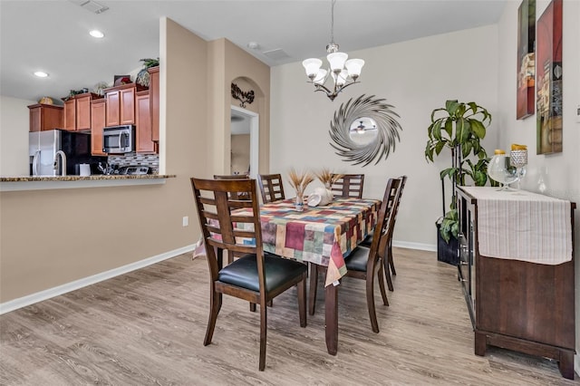 dining area with light hardwood / wood-style floors and a chandelier