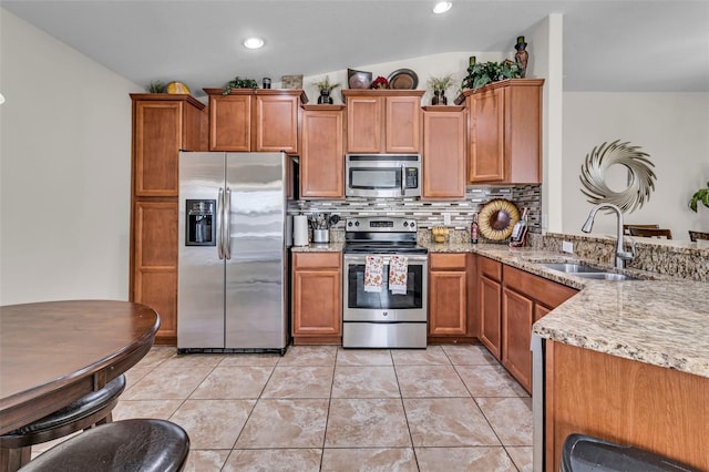 kitchen with sink, stainless steel appliances, light stone counters, vaulted ceiling, and decorative backsplash