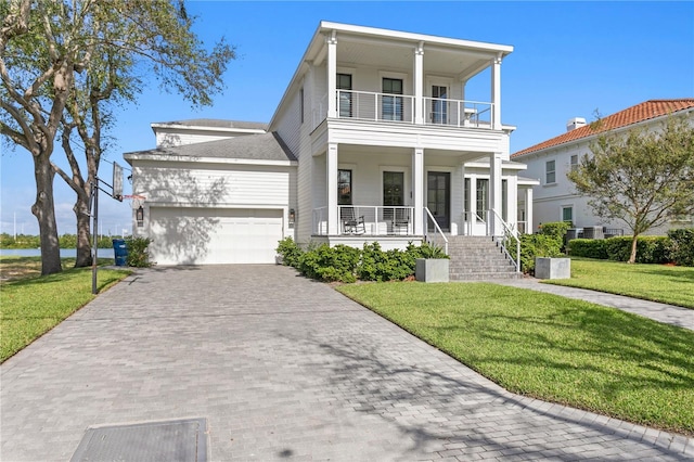 view of front of house with a front yard, a balcony, a garage, and covered porch