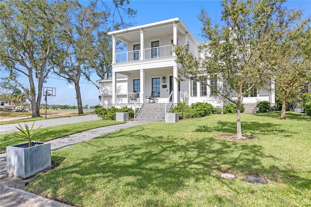 view of front of home with a front yard, a balcony, and covered porch