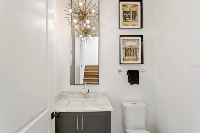 bathroom featuring an inviting chandelier, vanity, and toilet