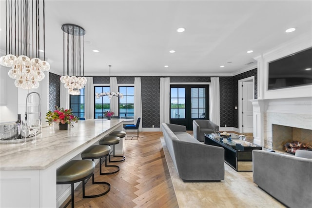 living room with a fireplace, ornamental molding, french doors, and a notable chandelier