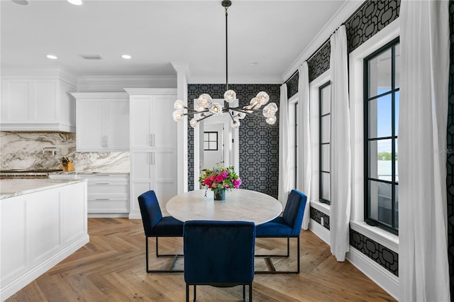 dining space with crown molding, light parquet flooring, and an inviting chandelier