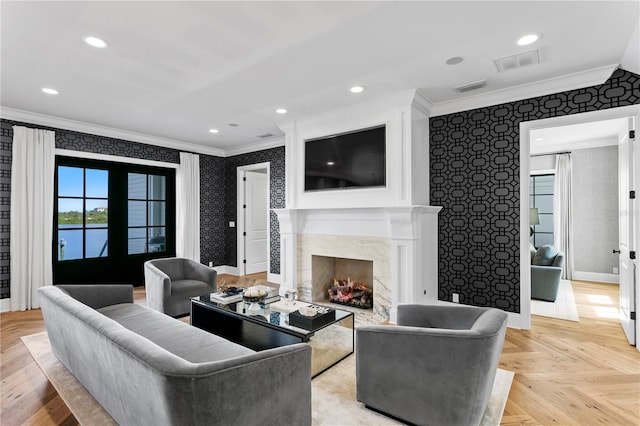 living room featuring light parquet flooring, crown molding, a fireplace, and french doors