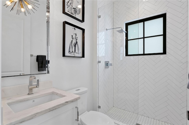 bathroom with a chandelier, vanity, toilet, and a shower with shower door