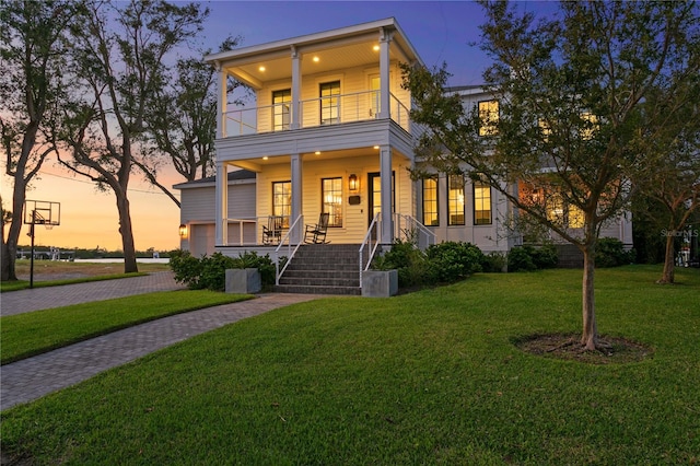 view of front facade with a yard, a balcony, and covered porch