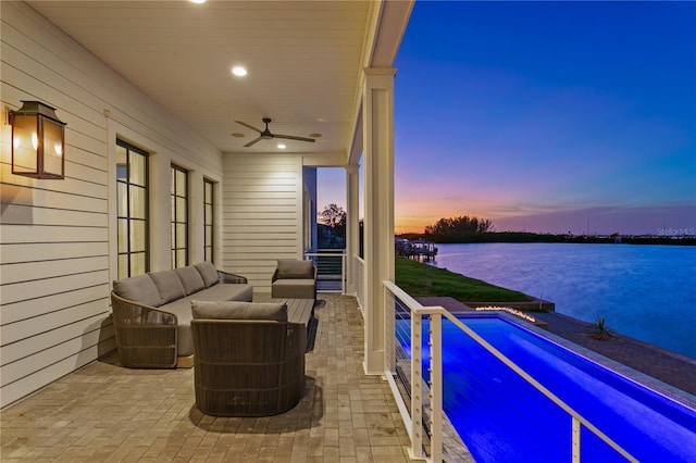 patio terrace at dusk featuring ceiling fan, a water view, and an outdoor hangout area