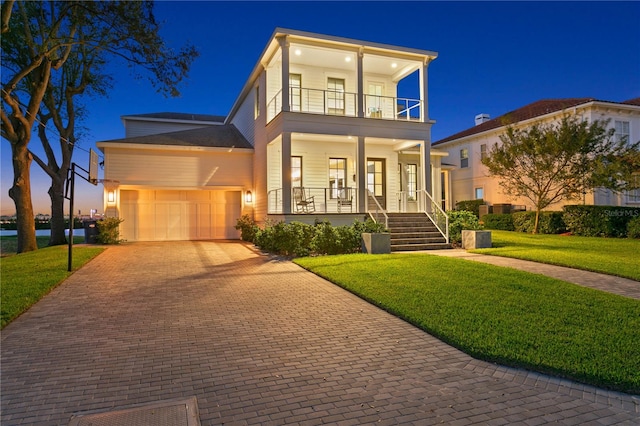 modern home featuring a porch, a yard, a balcony, and a garage