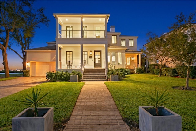 view of front of house featuring a porch, a yard, a balcony, and a garage